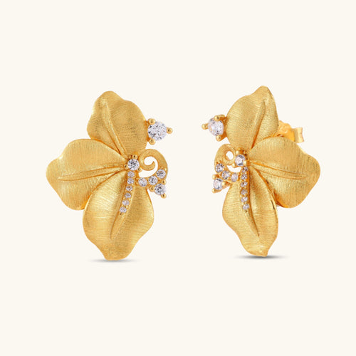 Gold-plated 925 silver flower stud earrings with brushed finish, swirl detail, and pavé cubic zirconia on cream background.
