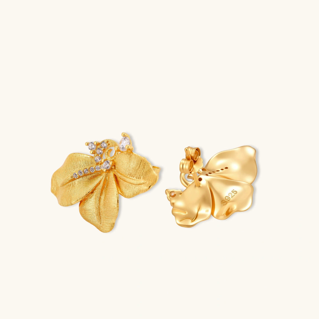 Gold-plated 925 silver flower stud earrings with brushed finish, swirl detail, and pavé cubic zirconia on cream background.