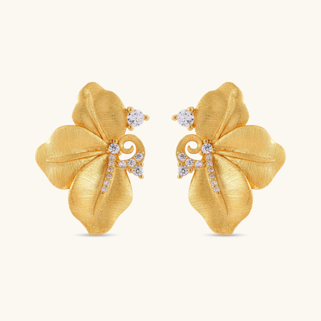 Gold-plated 925 silver flower stud earrings with brushed finish, swirl detail, and pavé cubic zirconia on cream background.