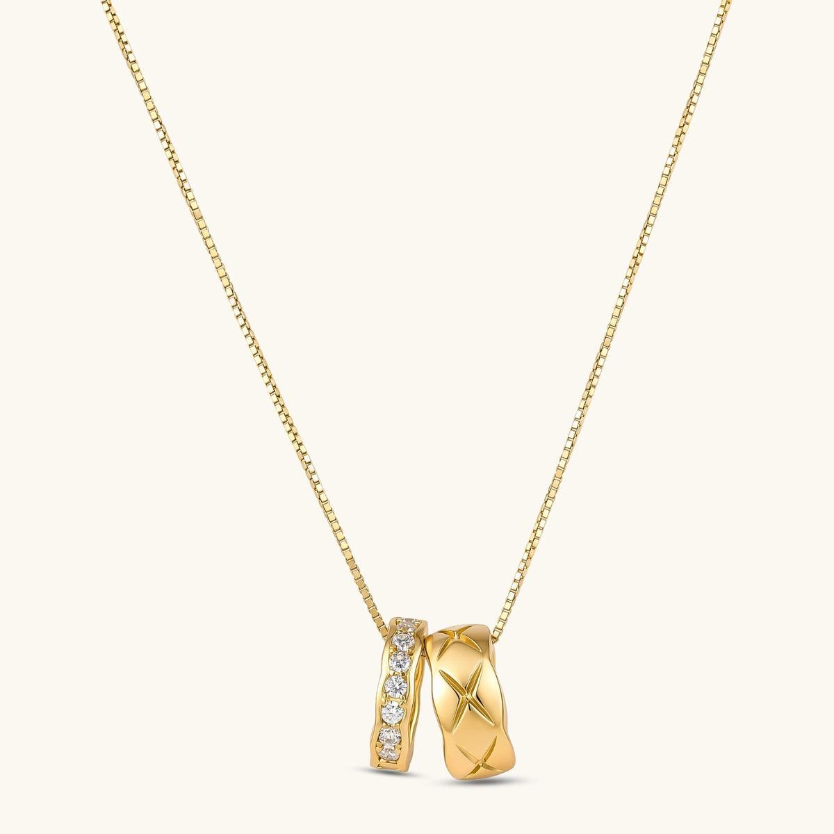 Gold box-chain necklace with two interlocking ring pendants — one star-engraved, one pavé cubic zirconia, 18K gold-plated.